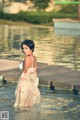 A woman in a white dress standing in a pool.