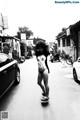 A woman in a bikini standing on a skateboard in the middle of a street.