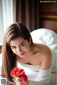 A woman in a white dress holding a red flower.