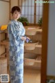 A woman in a blue and white kimono standing in a room.