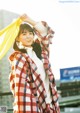 A woman in a plaid coat holding a yellow bag.