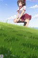 A girl in a school uniform crouching on a grassy hill.