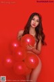 A woman holding a bunch of red balloons.