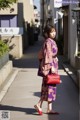 A woman in a purple kimono is walking down the street.