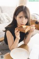 A woman sitting at a table eating a piece of bread.