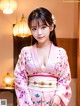 A woman in a pink kimono posing for a picture.