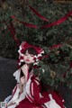 A woman in a red and white dress sitting under a tree.