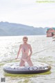 A woman in a pink bikini standing on an inflatable boat.