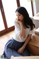 a woman sitting on top of a wooden table next to a window