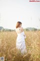 A woman in a white dress standing in a field.