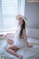 A woman sitting on a bed wearing a straw hat.