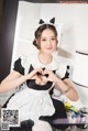 A woman in a maid outfit making a heart with her hands.