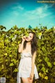 A woman in a white dress standing in a vineyard.