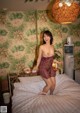 A naked woman standing on a bed in a room.