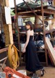 A woman in a black dress standing in front of a pile of junk.