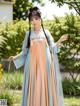 A woman in a blue and orange hanfu dress standing in a garden.