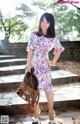 A woman in a floral dress is posing for a picture.