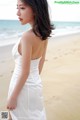 A woman in a white dress standing on a beach.