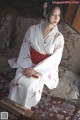 A woman in a white and red kimono sitting on a couch.